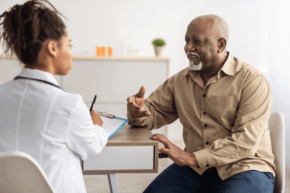 Médica conversando com paciente idosa durante consulta.