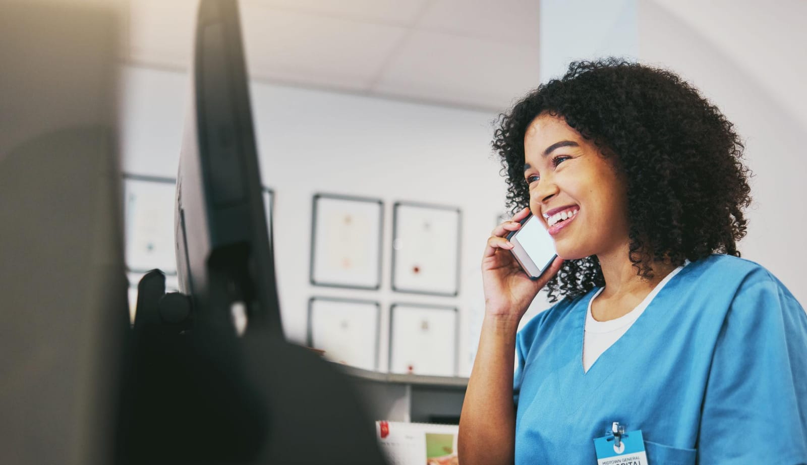 Enfermeira ao telefone em frente ao computador, em contato com paciente.